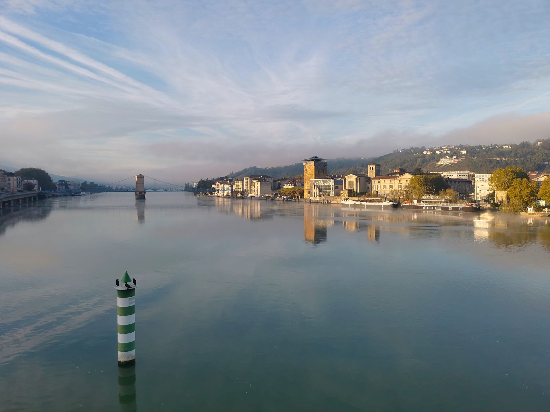 Le Rhône au lever du jour, calme comme un miroir, avec les quais au loin